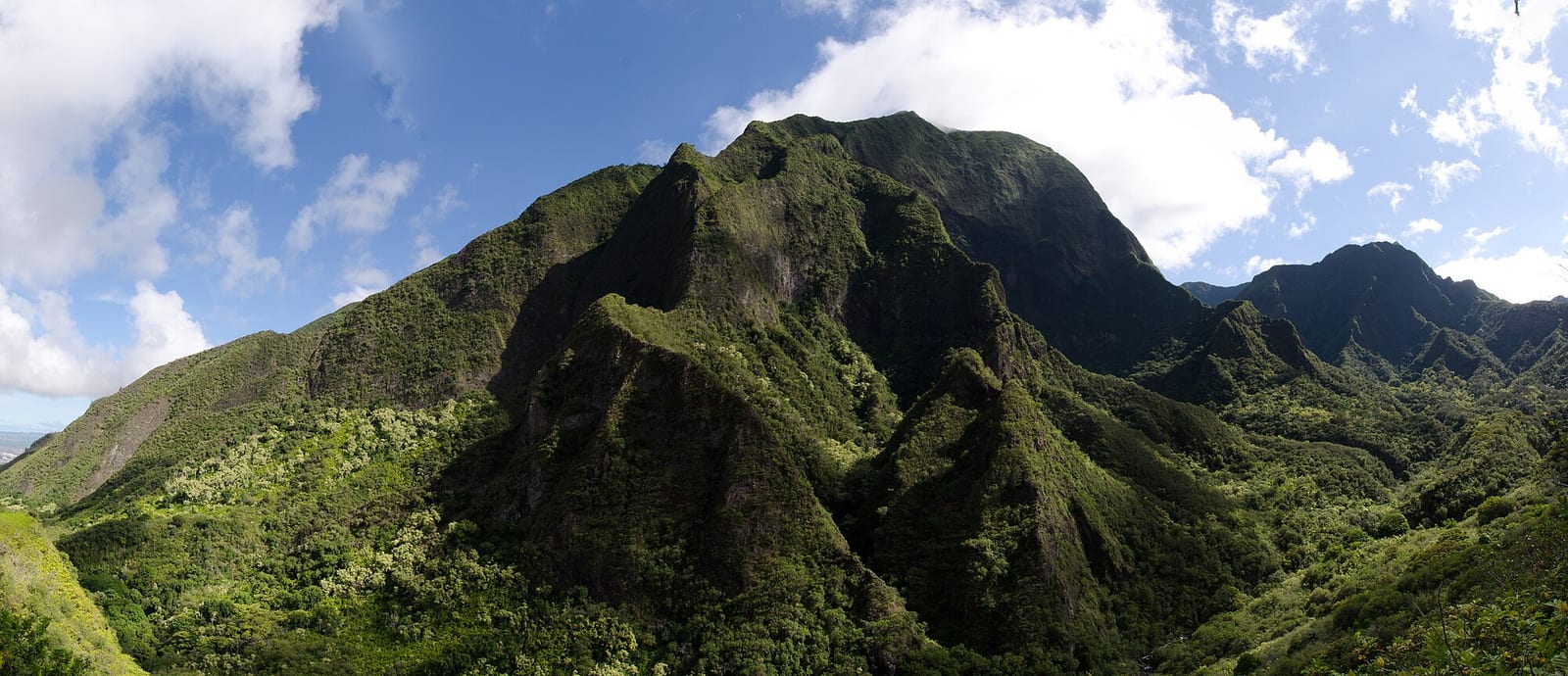 Steep green ridges of the West Maui Mountains around ʻĪao Valley under a partly cloudy sky