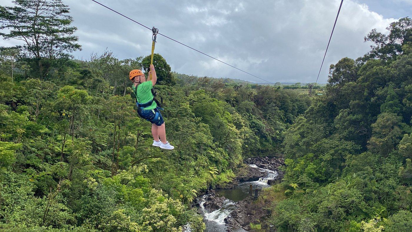 Young zipline guest riding solo above the rainforest canopy and river gorge at the Umauma Falls zipline course.