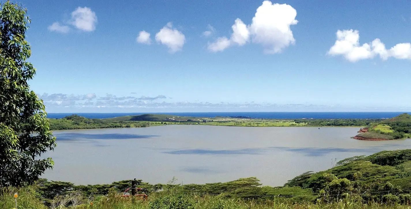 Overlook of the Waita Reservoir and Kauaʻi's South Shore, with the Pacific Ocean on the horizon beyond the surrounding countryside.