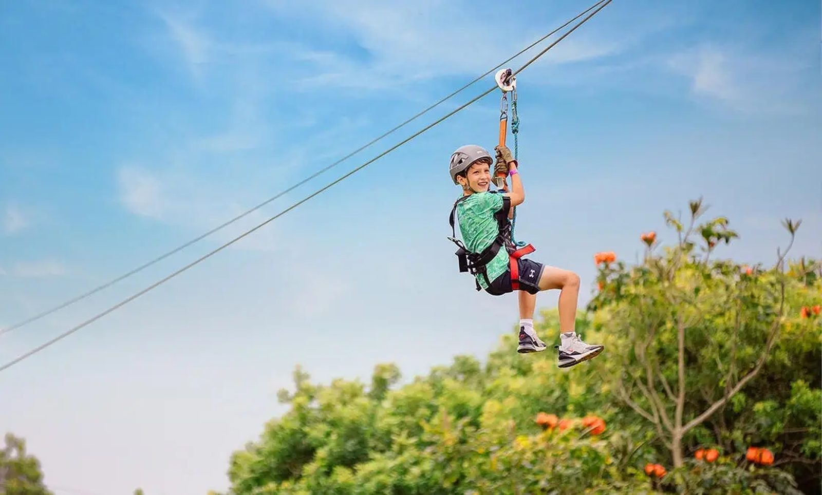 Young guest smiling while ziplining above the treetops on the NorthShore Zipline Tour, Maui