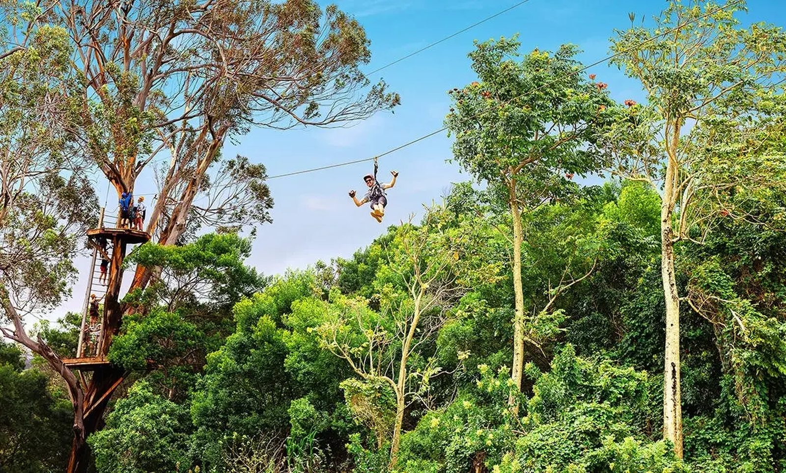 Guest ziplining away from a high launch tower over the North Shore treetops on the NorthShore Zipline Tour, Maui