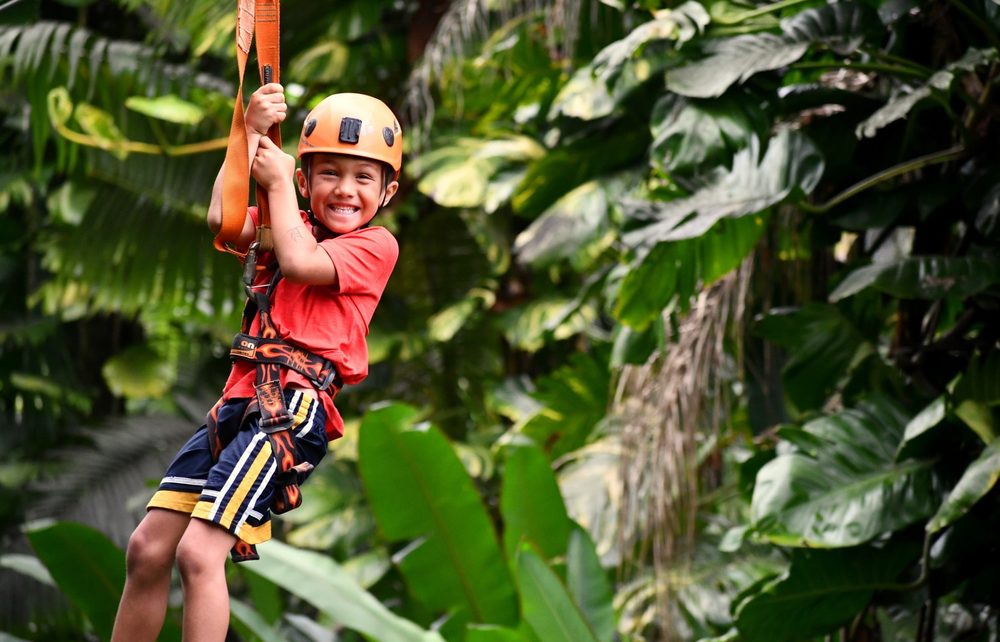 Young guest smiling while ziplining through the rainforest canopy on the 8-Line Zipline Eco Tour, Maui